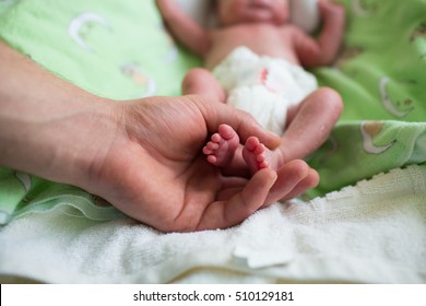 father holding premature baby legs