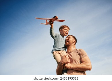 Father is holding son that playing with toy plane. - Powered by Shutterstock