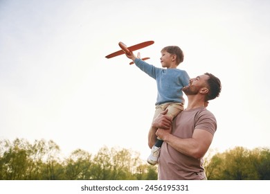 Father is holding son that playing with toy plane. - Powered by Shutterstock