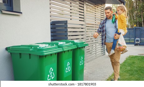 Father Holding A Young Girl And Going To Throw Away An Empty Bottle And Food Waste Into The Trash. They Use Correct Garbage Bins Because This Family Is Sorting Waste And Helping The Environment.