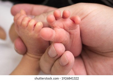 Father holds his baby's foot. Newborn little toes in parent's hands