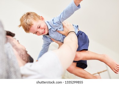 Father holds up his happy son while playing and romping