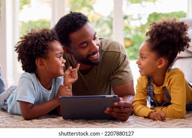 Father At Home Lying On Rug In Lounge With Children Using Digital Tablet - Powered by Shutterstock