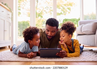 Father At Home Lying On Rug In Lounge With Children Using Digital Tablet - Powered by Shutterstock