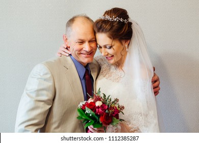 Father Hugs Her Daughter To The Bride Who Holds A Wedding Bouquet In Her Hands