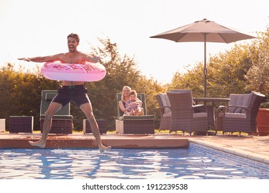 Father With Inflatable Ring Jumps Into Outdoor Pool On Summer Vacation Watched By Mother And Son