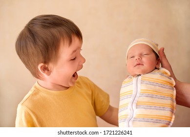 Father Introduces To Little Toddler Boy Infant Baby Sister. Portrait Of Little Kid With Hilarious Face And Open Mouth Looking At Sleeping Newborn Child. Elder Brother Meets Newborn New Family Member