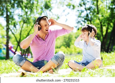 Father and kid in summer park enjoying music - Powered by Shutterstock