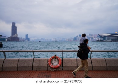 Father And Kid Walking On Hong Kong Promenade.