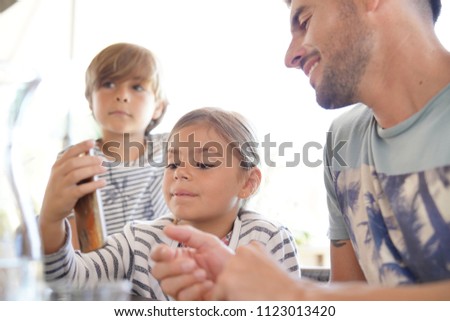 Father with kids playing with smartphone at restaurant