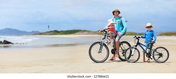 Father And Kids Riding Bikes Along A Beach