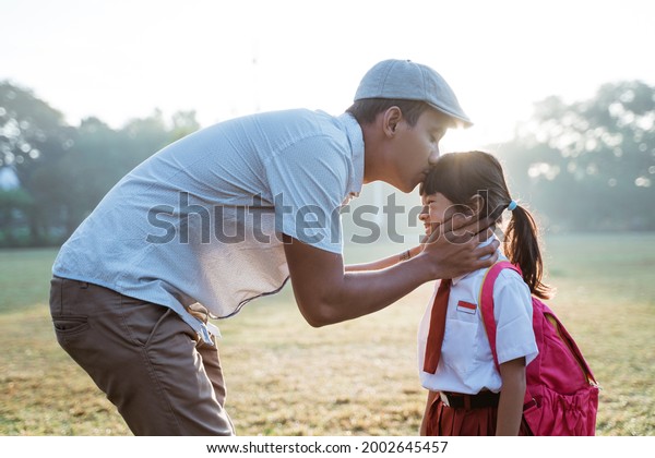 father kiss her\
daughter forehead when taking her to school in the morning. primary\
student first day