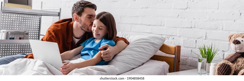 Father Kissing Happy Daughter Using Laptop In Hospital Bed, Banner