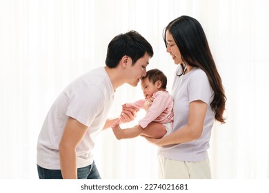 father kissing newborn baby while mother holding her on white window background. happy family concept - Powered by Shutterstock