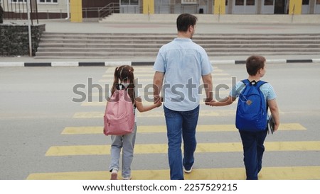father leads children to school through pedestrian crossing. happy family. zebra road. group child girl boy go to school with school backpacks. happy family concept. school students. parent with kid