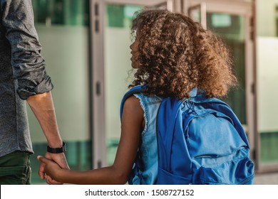 Father leads a little child school girl at first grade. Little cute african school girl going to school with her dad