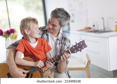 Father Learning His Boy To Play Guitar