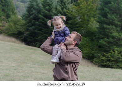 Father Lifting A Cheerful Toddler Daughter Outdoors In Nature