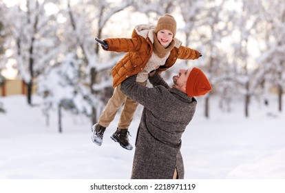 Father lifting little son up while having fun together outdoor on frosty day, happy dad and kid playing in winter park, enjoying snowy weather, actively spending New year holidays on fresh air - Shutterstock ID 2218971119