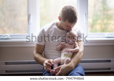 A Father and little baby sit on the floor together