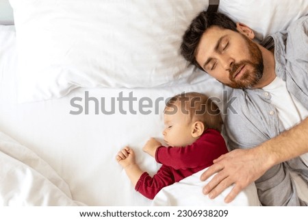 Father and little baby sleeping together in bed.
