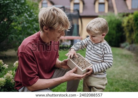 Father with little boy making bug hotel, or insect house outdoors in the garden. Boy learning about insects, garden ecosystem and biodiversity. [[stock_photo]] © 
