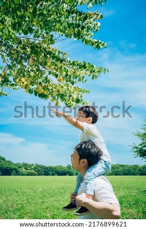 a father and a little boy walking on the green space with piggybacks