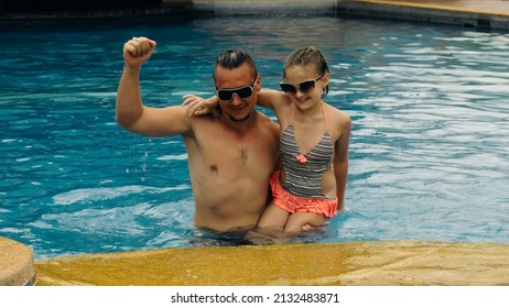 The Father With Little Daughter Have Fun In The Pool. Dad Plays With The Child. The Family Enjoy Summer Vacation In A Swimming Pool Jumping, Spinning, Splash Water. Slow Motion.