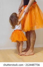 Father and little girl are wearing matching ballerina dresses and dancing