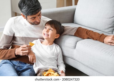 Father And Little Son Eating Tasty Chips At Home