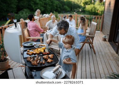 Father with little son grilling outside during family summer garden party. - Powered by Shutterstock