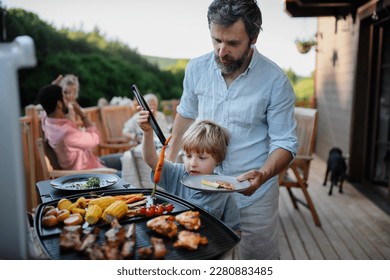 Father with little son grilling outside during family summer garden party. - Powered by Shutterstock