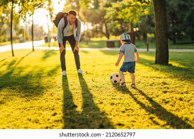 father with a little son plays football on the green grass in the park. Happy family having fun and playing football on a green grassy lawn on a sunny day. Family concept, Father's Day - Powered by Shutterstock