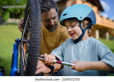 Father with little son together preparing bicycle for a ride, pumping up tyres in garden in front of house. - Powered by Shutterstock