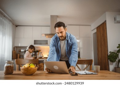 Father look and read document at the laptop while son use mobile phone at background - Powered by Shutterstock