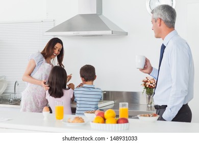 Father Looking At His Family Cooking In The Kitchen Before Work In The Morning