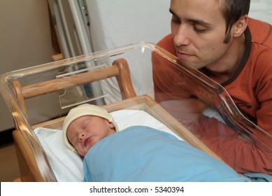 Father Is Looking At Newborn Baby In Hospital