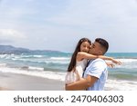A father lovingly kisses his daughter as he holds her by the beach. The girl