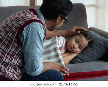 Father lovingly tuck cute little daughter to sleep on sofa in the living room at home. Daddy daughter love and bonding relationship. Single father, Father's day concept.