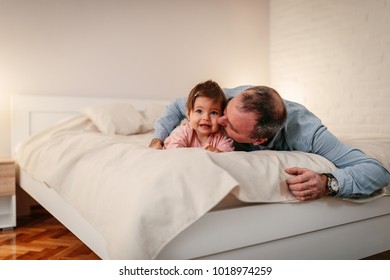 Father Lying On Bed , Kissing A Baby Girl