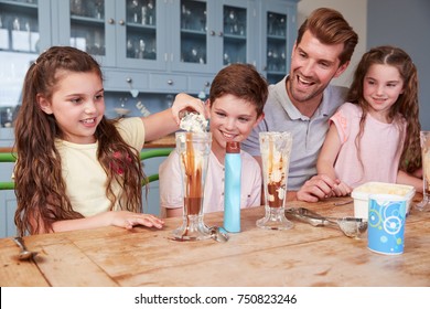 Father Making Ice Cream Sundaes With Children At Home