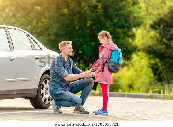 Father meeting little school girl after classes\
on parking
