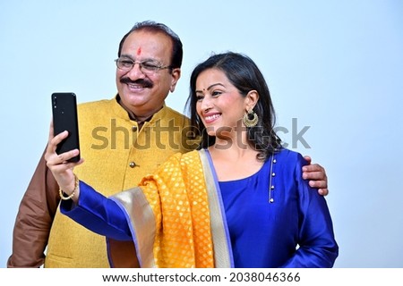 Father with middle age daughter in tradional wear taking selfie