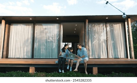 Father, mother and daughter focus laptop at terrace with garden view outside house. Parent use outdoor activity to communicate young generation about environment care cross generation gap. Divergence. - Powered by Shutterstock