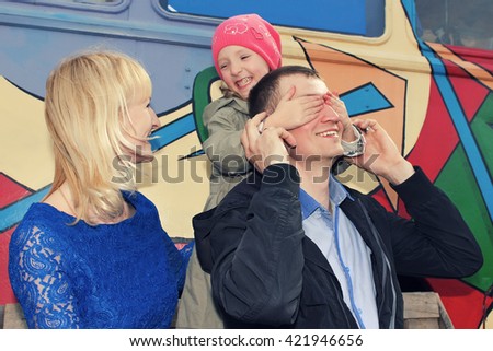 Father, mother and daughter making a joke or playing hide and seek.