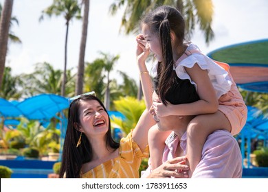 Father And Mother And Daughter Play At The Amusement Park. Family In Theme Park.