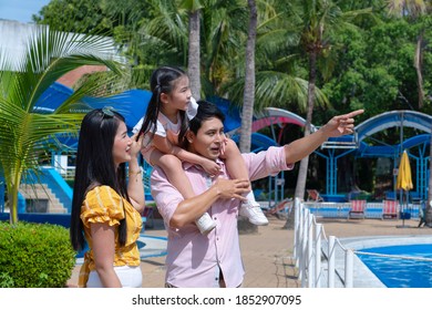 Father And Mother And Daughter Play At The Amusement Park. Family In Theme Park.