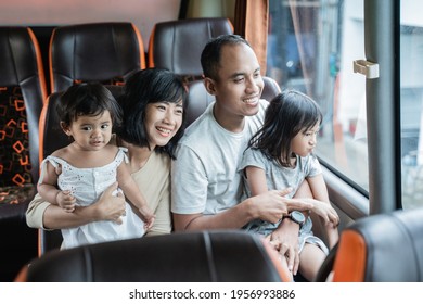 The Father And Mother Held Their Two Children While Sitting On The Bus Bench During The Trip