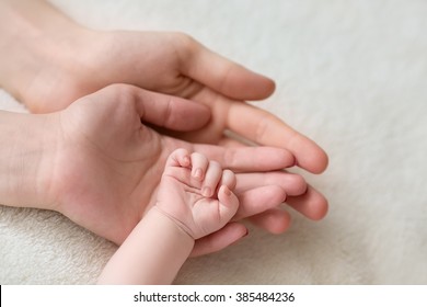 father and mother hold in their hands a little newborn baby's ha