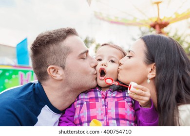 Father, mother kissing their daughter blowing bubbles, amusement - Powered by Shutterstock